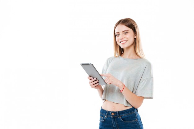 Ritratto di una ragazza sorridente che sta e che tocca il computer della compressa