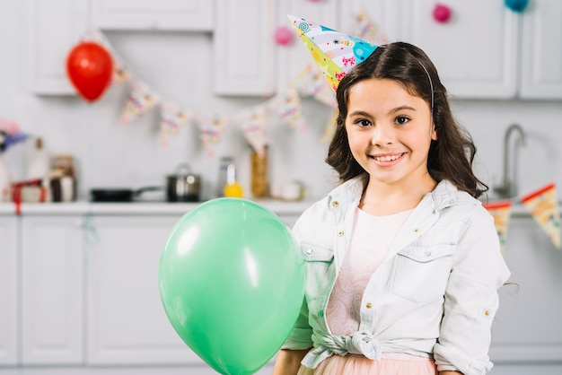 Ritratto di una ragazza sorridente con palloncino verde rivolto verso l&#39;obiettivo