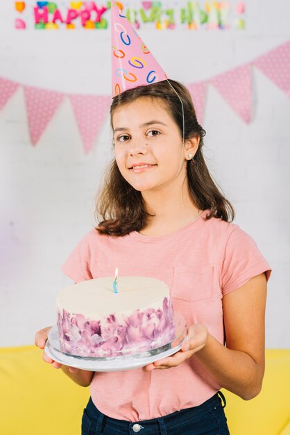 Ritratto di una torta di compleanno sorridente della tenuta della ragazza