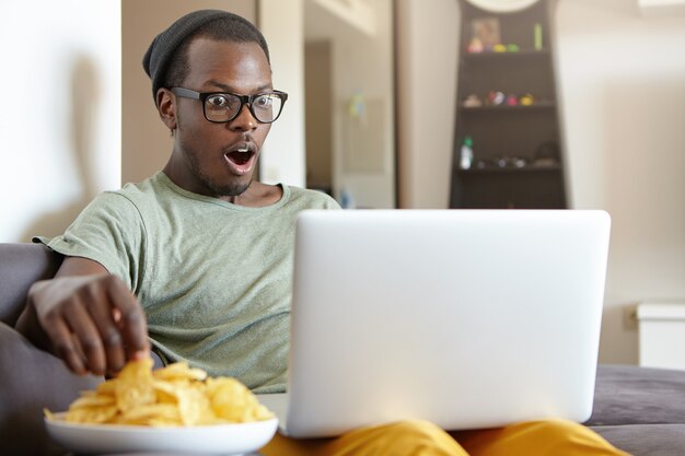 Ritratto di uomo afro-americano alla moda con il computer portatile a casa