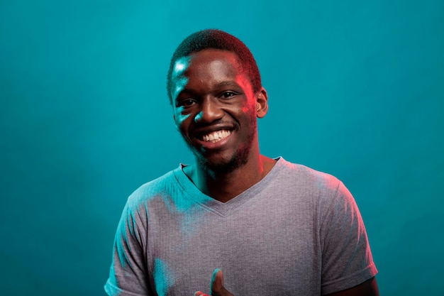 Ritratto di uomo allegro sorridente e guardando la fotocamera in studio, con espressioni facciali naturali e sorriso. Persona sicura che gode di uno stile di vita felice con emozioni positive in studio.