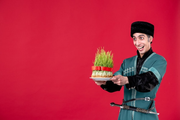 Ritratto di uomo azero in costume tradizionale che tiene semeni verde su ballerino rosso feste etniche novruz primavera