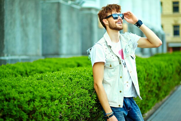 Ritratto di uomo bello in abiti eleganti hipster. Ragazzo attraente in posa in strada