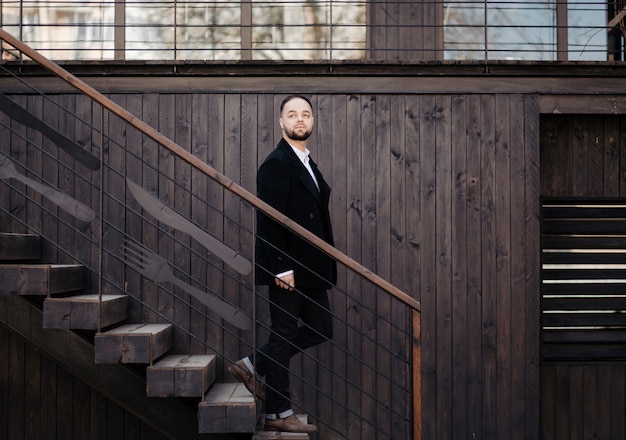 Ritratto di uomo ben vestito alla moda con la barba in posa all'aperto