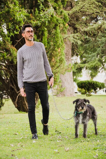 Ritratto di uomo che cammina con il suo cane sull&#39;erba verde nel parco