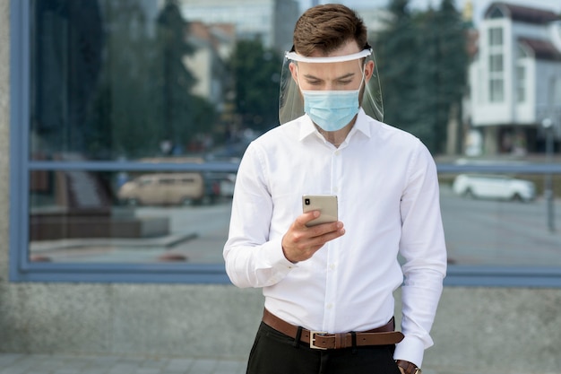 Ritratto di uomo con maschera utilizzando il cellulare