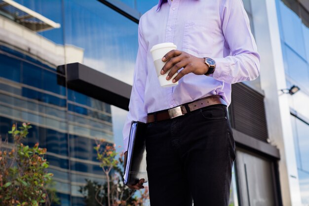 Ritratto di uomo d'affari afro prendendo una pausa dal lavoro e bere una tazza di caffè all'aperto. Concetto di affari.