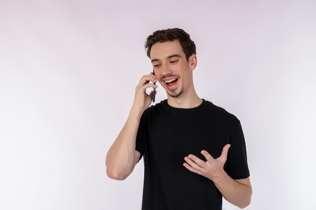 Ritratto di uomo d'affari bello felice parlando dal telefono cellulare e in piedi isolato su sfondo bianco