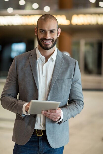 Ritratto di uomo d'affari sorridente utilizzando tavoletta digitale in sala d'attesa