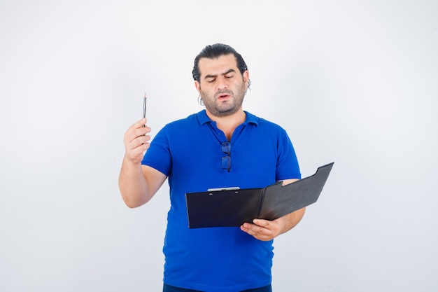 Ritratto di uomo di mezza età con appunti mentre tiene la matita in polo t-shirt