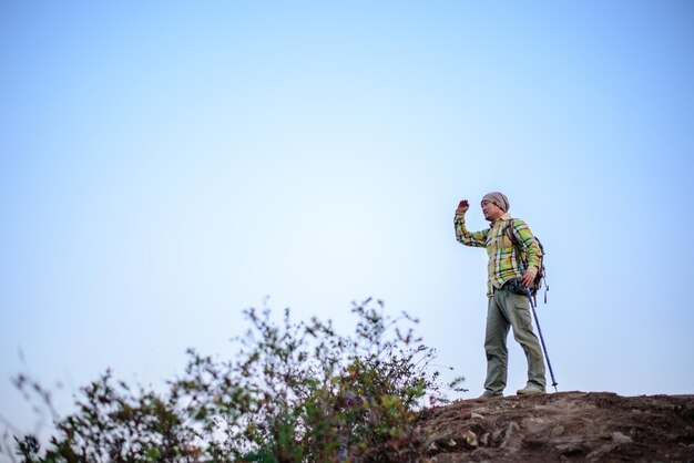 Ritratto di uomo escursionista in piedi sulla cima di una montagna o di una scogliera e guardando sulla valle con spazio di copia Concetto di avventura vacanze estive all'aperto da solo in natura