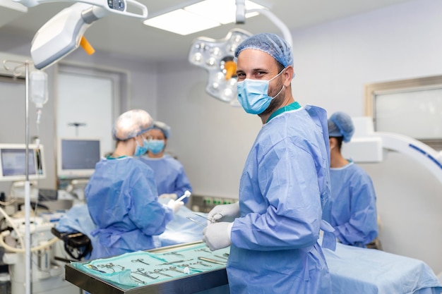 Ritratto di uomo felice chirurgo in piedi in sala operatoria pronto a lavorare su un paziente Operatore medico maschio in uniforme chirurgica in sala operatoria