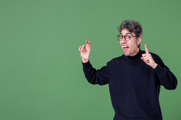 Ritratto di uomo genio vestito casualmente in studio girato su parete verde