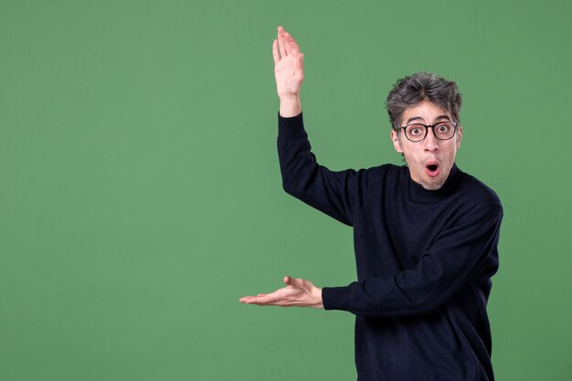 Ritratto di uomo genio vestito casualmente in studio girato su parete verde