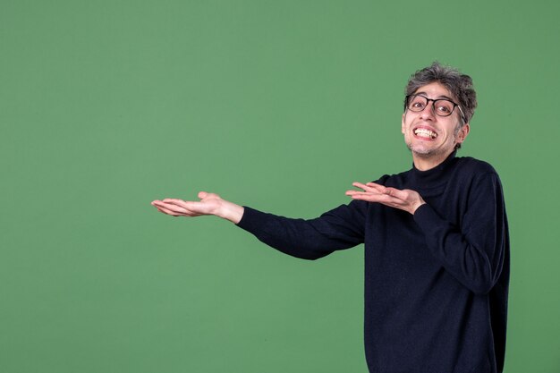 Ritratto di uomo genio vestito casualmente in studio girato su parete verde