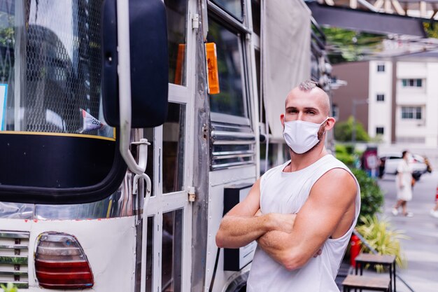 Ritratto di uomo in maschera medica bianca sulla piazza centrale della città si siede su una sedia in van cafe