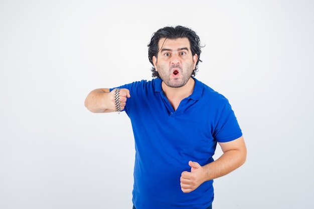 Ritratto di uomo maturo minacciando con catena avvolta da un pugno in maglietta blu e guardando aggressivo vista frontale