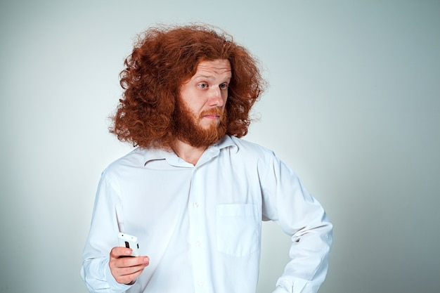 Ritratto di uomo perplesso parlando al telefono una parete grigia