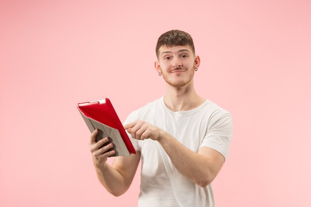 Ritratto di uomo sorridente che punta al computer portatile con schermo vuoto isolato su studio rosa