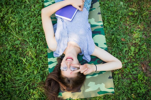 Ritratto di vista dall'alto di una donna abbastanza giovane che si distende su un'erba nel parco