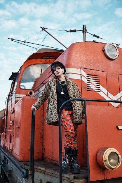 Ritratto estetico pop punk di donna in posa da una locomotiva