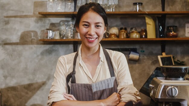 Ritratto giovane donna asiatica barista sentirsi sorridenti al caffè urbano.