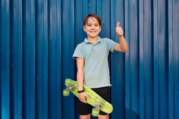 Ritratto Giovane ragazzo sorridente cool in polo blu in posa con PENNY BOARD nelle mani