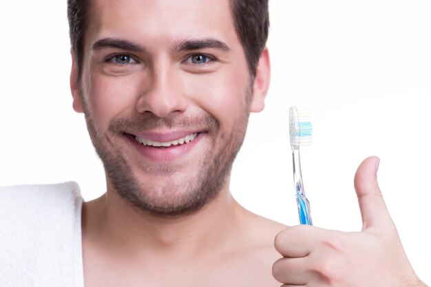 Ritratto in primo piano di un giovane felice con uno spazzolino da denti - isolato su bianco.