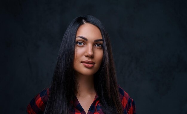 Ritratto in studio di donna bruna glamour hipster vestita con una camicia in pile rossa su sfondo grigio.