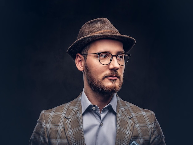 Ritratto in studio di un hipster barbuto con cappello e occhiali