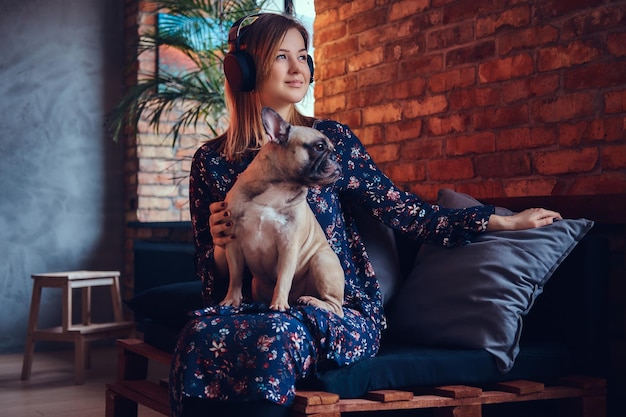 Ritratto in studio di una bionda attraente e felice in una stanza con interni soppalcati.