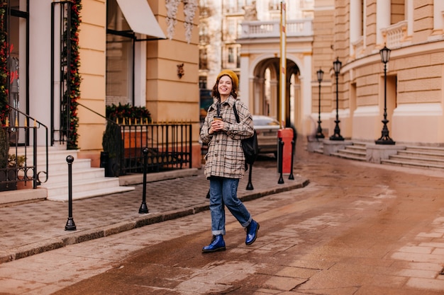 Ritratto integrale della studentessa che cammina nel centro della città. donna in scarpe blu