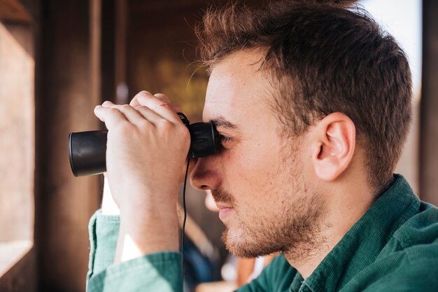 Ritratto laterale di un uomo che osserva tramite il binocolo