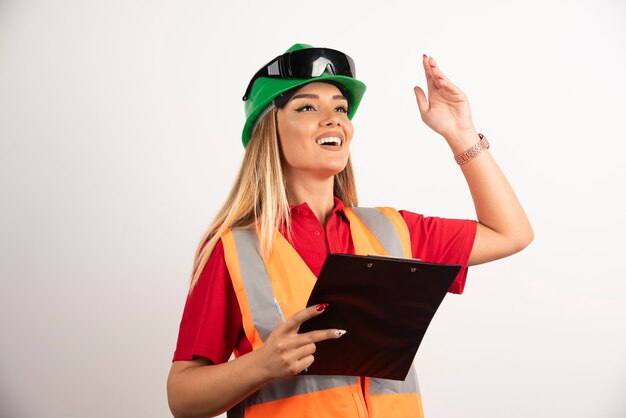 Ritratto lavoratore donna industria indossando uniformi di sicurezza e occhiali in piedi su sfondo bianco.