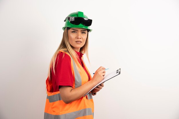 Ritratto lavoratore donna industria indossando uniformi di sicurezza e occhiali in piedi su sfondo bianco.