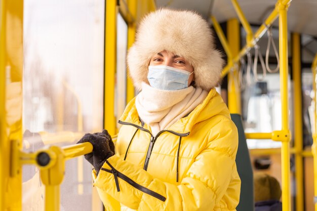 Ritratto luminoso e soleggiato di una giovane donna in vestiti caldi in un autobus urbano in una giornata invernale