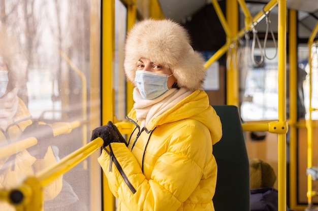 Ritratto luminoso e soleggiato di una giovane donna in vestiti caldi in un autobus urbano in una giornata invernale