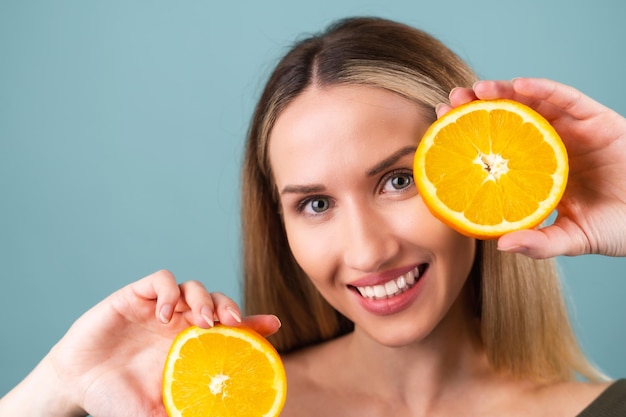 Ritratto ravvicinato di donna in topless con pelle perfetta e trucco naturale, labbra completamente nude, con in mano un'arancia fresca di vitamina C agrumata