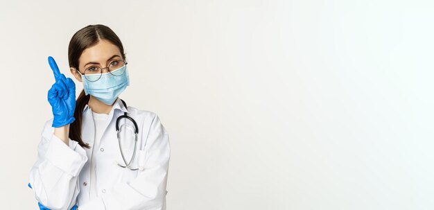 Ritratto ravvicinato di dottoressa in occhiali maschera medica e guanti che punta il dito verso lin