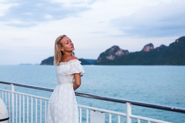 Ritratto romantico della donna in vestito bianco che naviga sul grande traghetto della barca