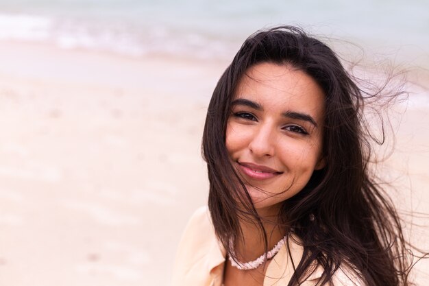 Ritratto romantico di donna sulla spiaggia in una giornata ventosa, luce calda del tramonto.