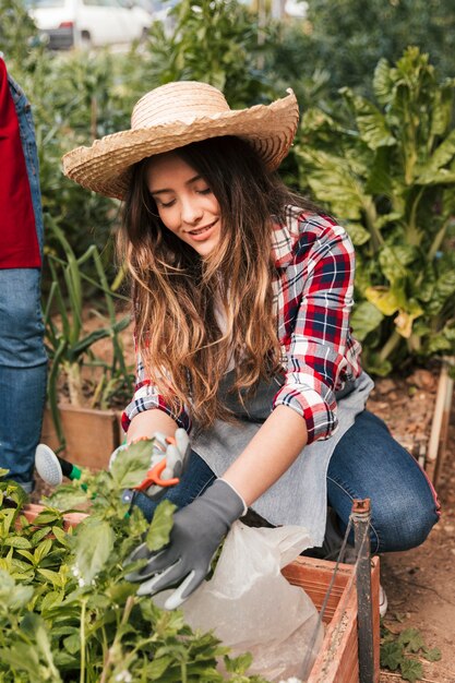 Ritratto sorridente di un giardiniere femminile che pota le piante