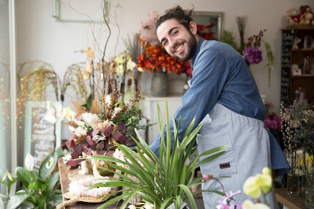 Ritratto sorridente di un giovane che sistema il fiore nel negozio di fiorista