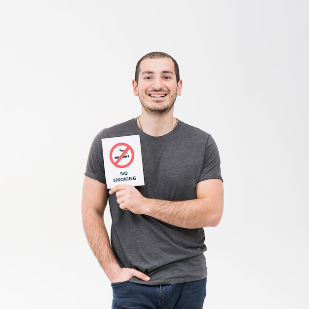 Ritratto sorridente di un uomo che mostra segno non fumatori con la mano in sua tasca isolata su fondo bianco