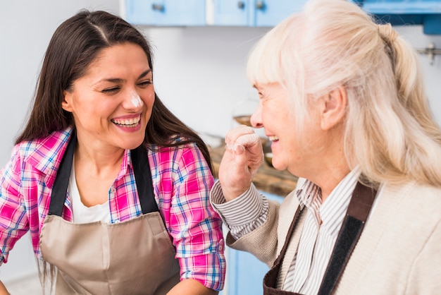 Ritratto sorridente di una donna senior che si diverte con la sua giovane figlia mentre preparava il cibo