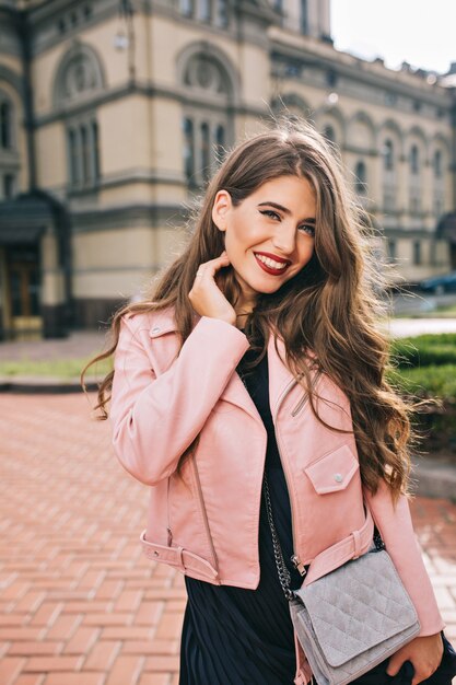 Ritratto verticale della bella ragazza con lunghi capelli ricci e labbra rosse in posa