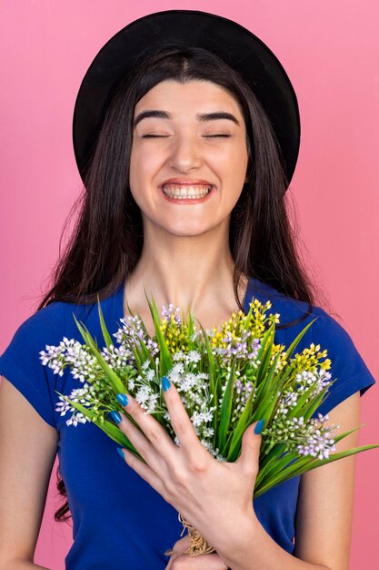 Ritratto verticale di giovane ragazza che tiene mazzo di fiori e ridendo