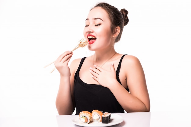 Ritratto vicino di bella donna che mangia i rotoli di sushi