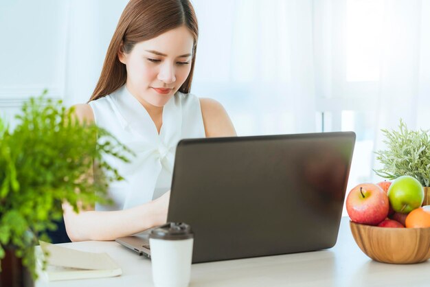 Riunione del vestito bianco della donna asiatica esecutiva astuta con il collega con il fondo dell'ufficio di presentazione del computer portatile