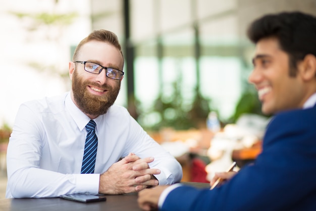 Riunione dell&#39;uomo barbuto bello sorridente con il socio commerciale